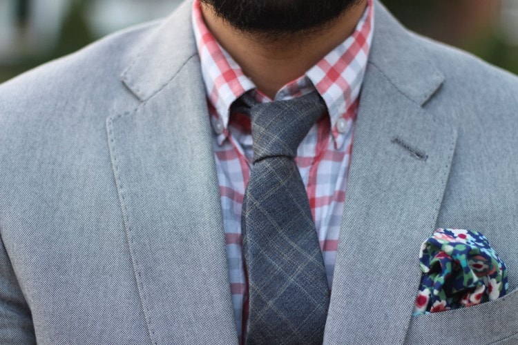 Gray suit paired with an orange plaid shirt and gray knitted plaid tie 