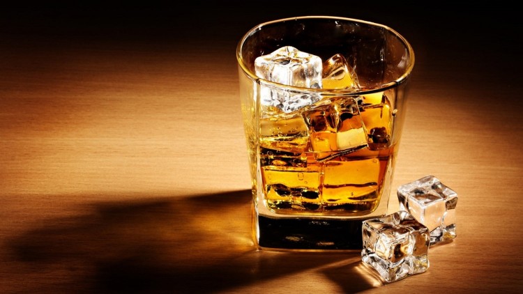 A full set of stereotypes - whiskey is poured into a rock glass and covered with a bunch of ice 